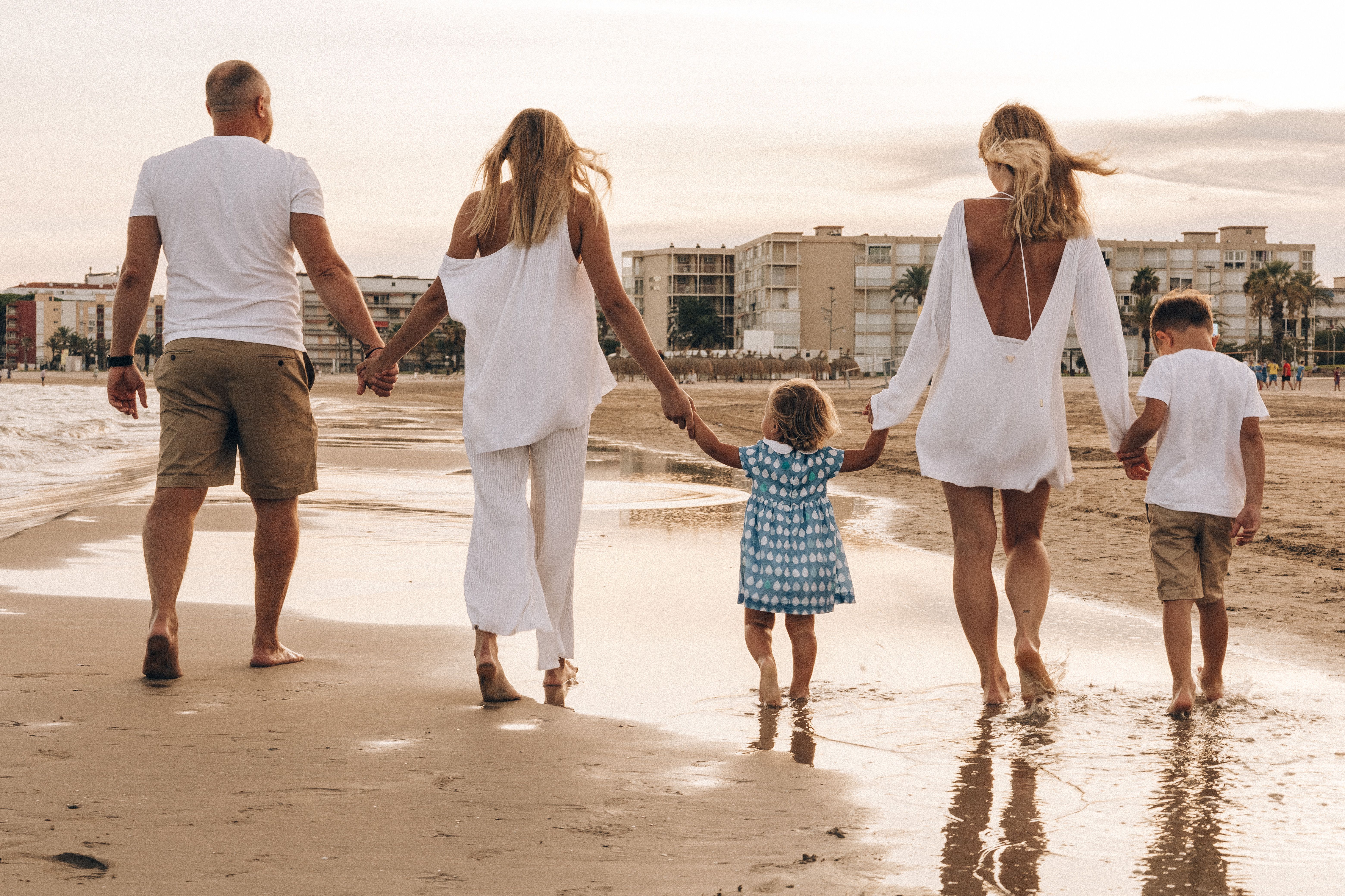 A family walking hand in hand along the beach at sunset