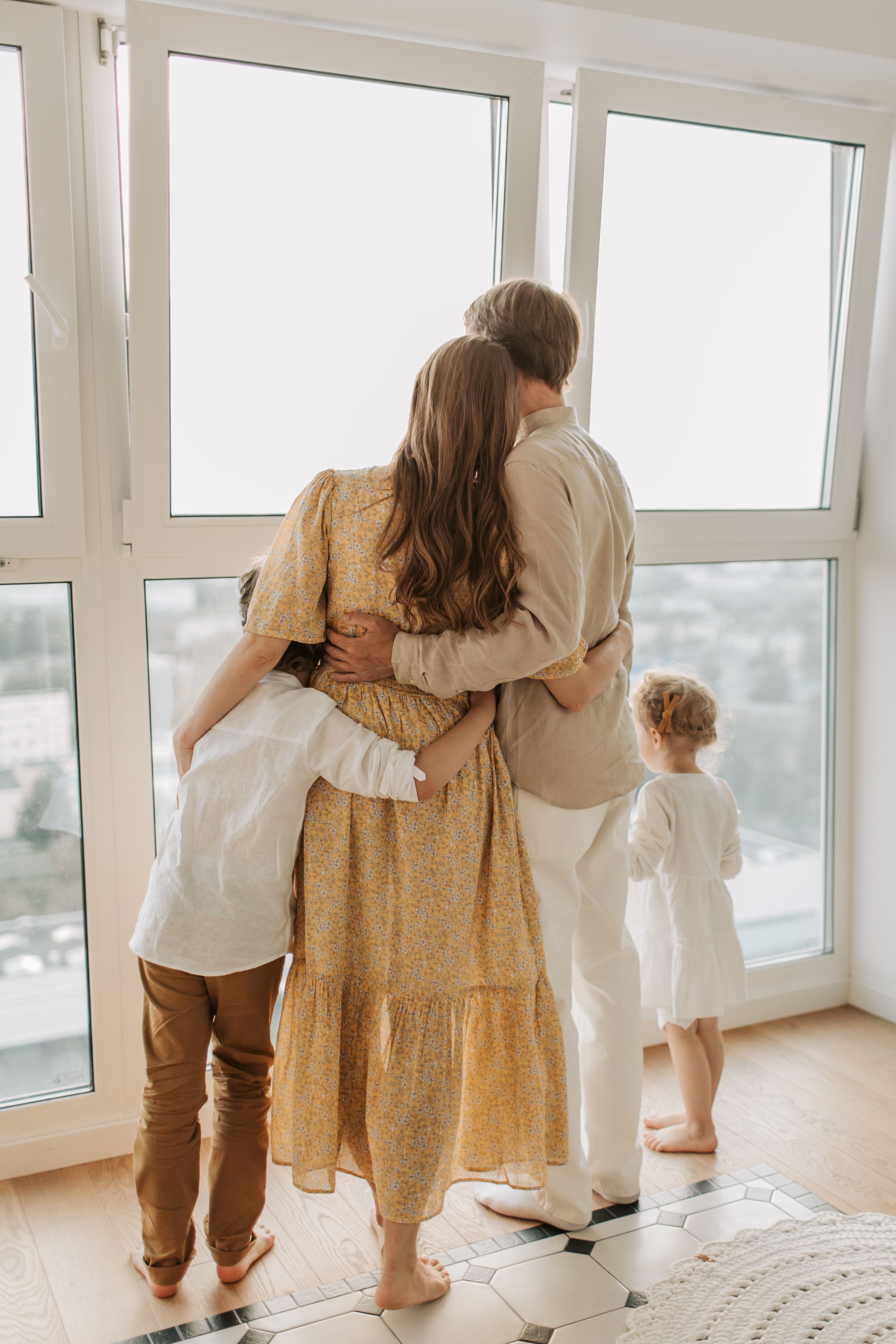 A family embracing as they look out a bright window together