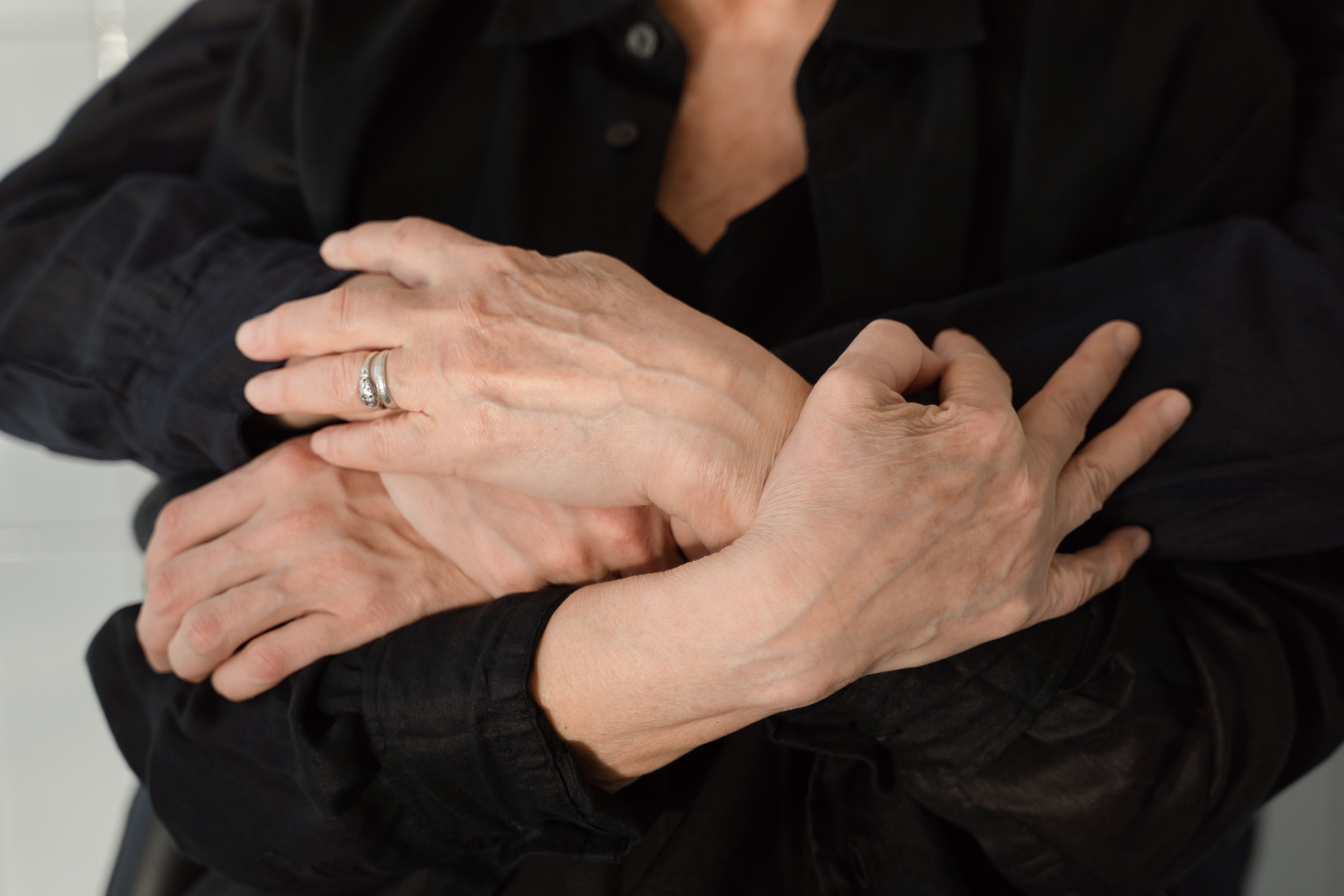 A couple holding each other close, hands gently clasped