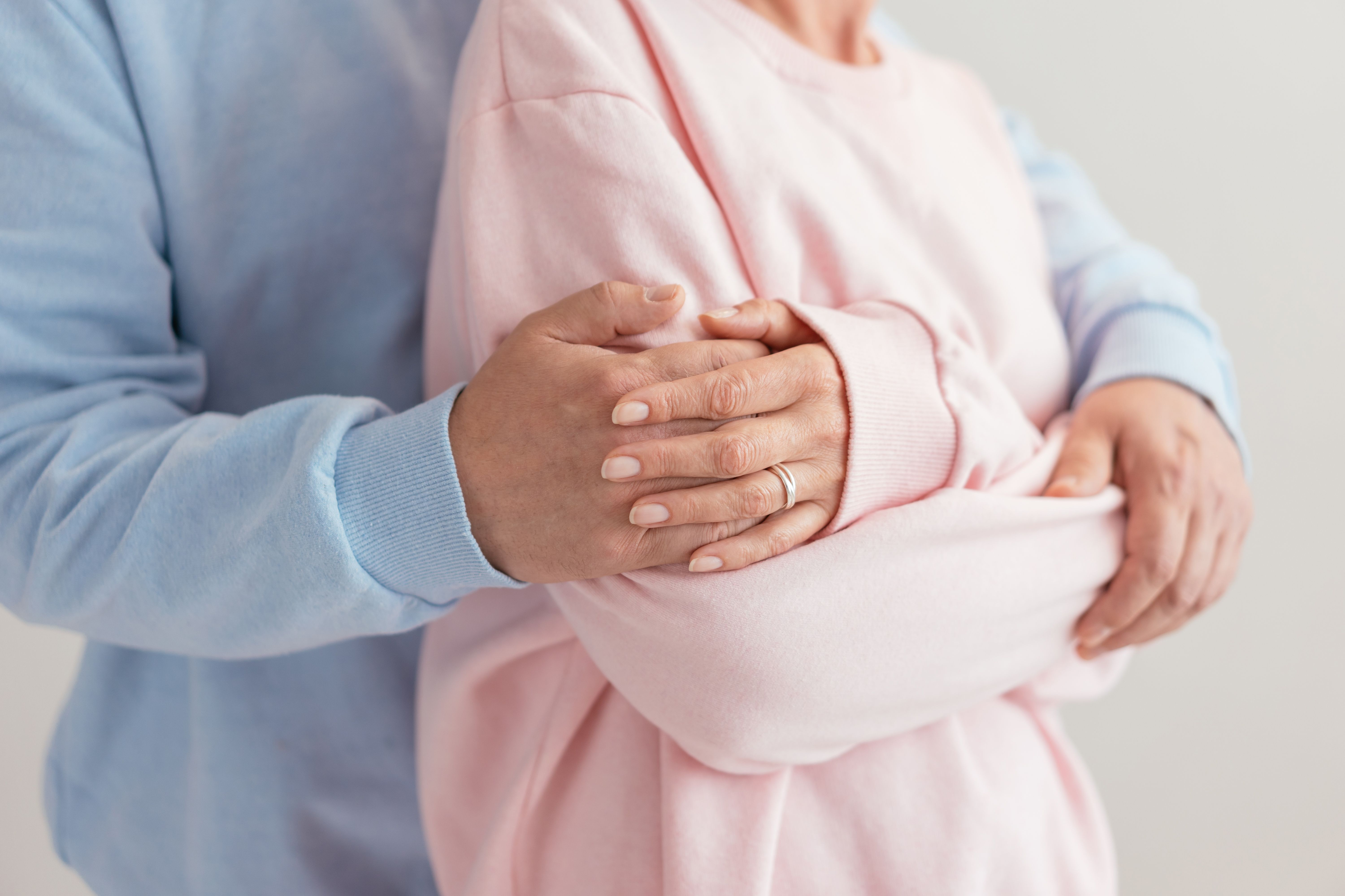 A couple in a warm embrace, hands held together